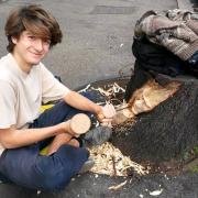 Incide dei volti sui tronchi tagliati degli alberi