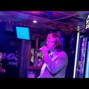Chris Martin travestito da uomo d'affari canta al karaoke. Il video